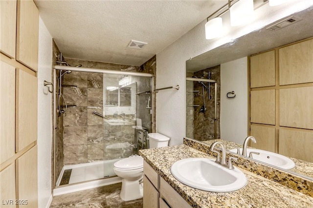 bathroom featuring vanity, a textured ceiling, a shower with door, and toilet