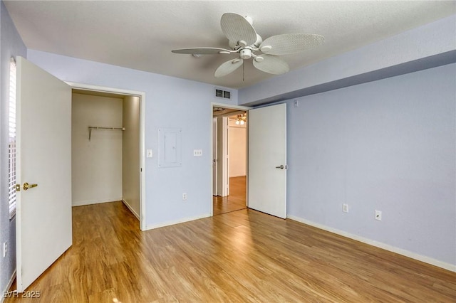 unfurnished bedroom featuring ceiling fan, a spacious closet, light wood-type flooring, and a closet