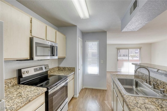 kitchen featuring stainless steel appliances, sink, light hardwood / wood-style flooring, and a textured ceiling