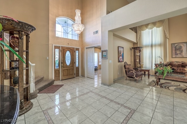 tiled foyer featuring an inviting chandelier and a high ceiling