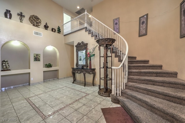 stairway with a towering ceiling and tile patterned floors