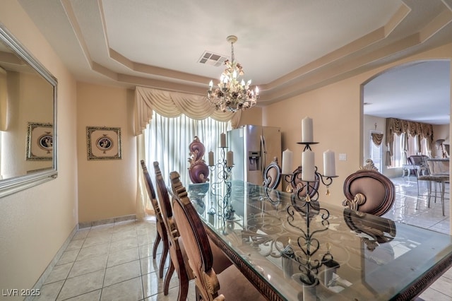 dining room featuring light tile patterned floors, a tray ceiling, and a chandelier