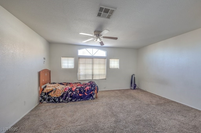 carpeted bedroom featuring ceiling fan and a textured ceiling