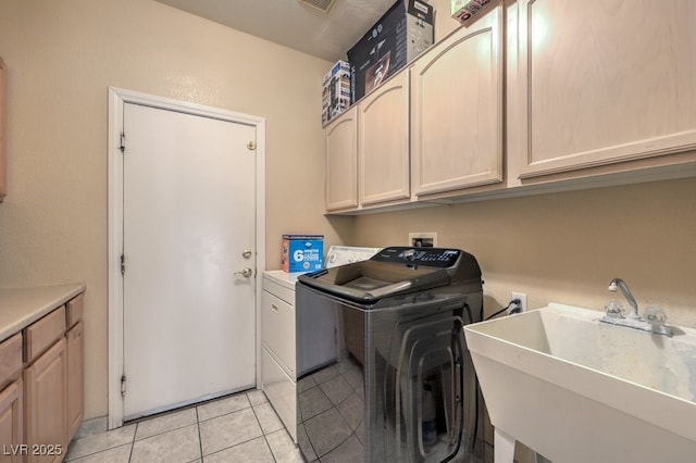 laundry area with cabinets, independent washer and dryer, sink, and light tile patterned floors