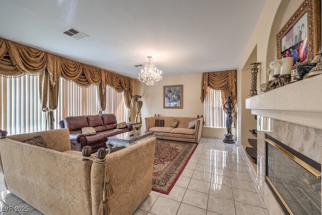 living room with a chandelier, a tiled fireplace, and light tile patterned flooring