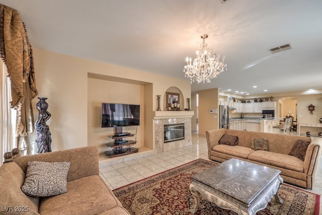 living room featuring an inviting chandelier, light tile patterned floors, and a tile fireplace