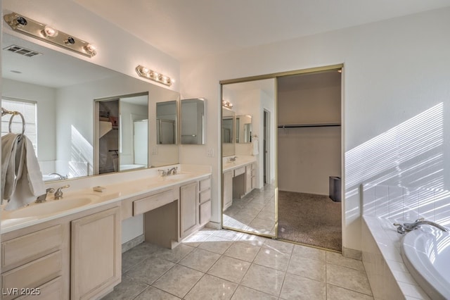 bathroom featuring a relaxing tiled tub, tile patterned floors, and vanity