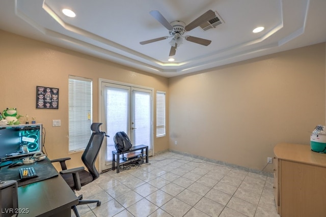 tiled office with ceiling fan and a tray ceiling