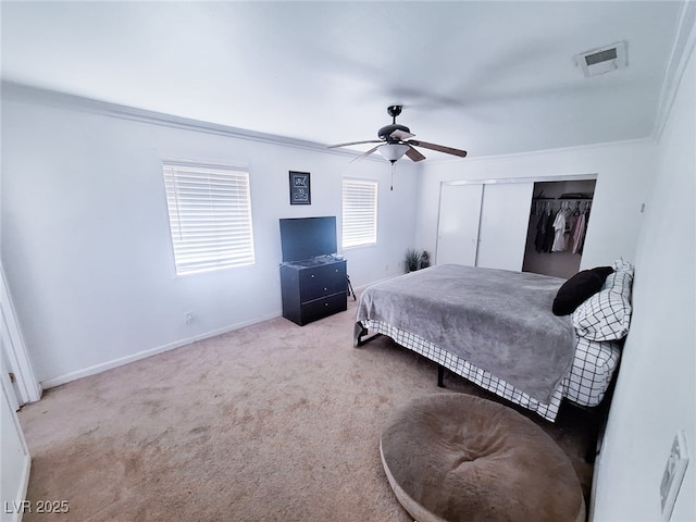 bedroom featuring ceiling fan, light colored carpet, ornamental molding, and a closet