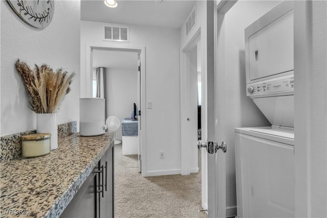 laundry area with stacked washer and dryer and light colored carpet