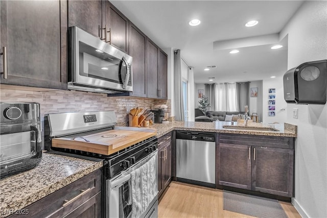 kitchen with sink, dark brown cabinets, stainless steel appliances, and light wood-type flooring