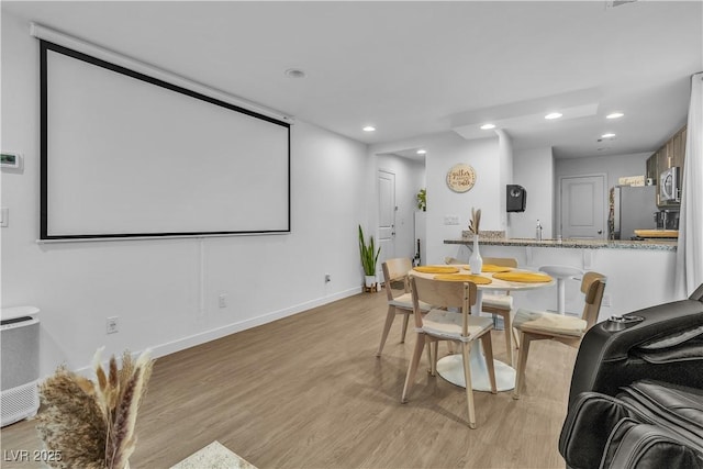 cinema room featuring sink and light wood-type flooring