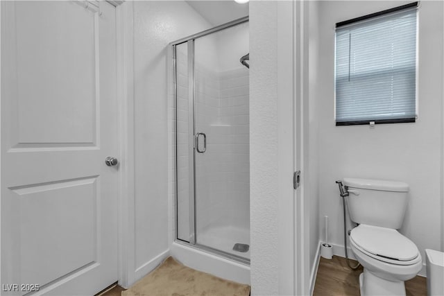 bathroom featuring wood-type flooring, a shower with shower door, and toilet