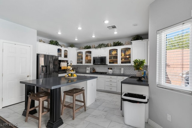 kitchen with stainless steel appliances, a center island, white cabinets, and a kitchen bar