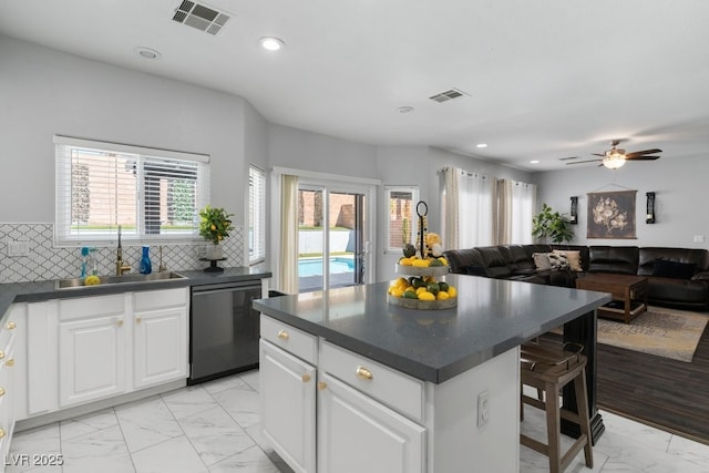 kitchen with a kitchen island, tasteful backsplash, dishwasher, sink, and white cabinets