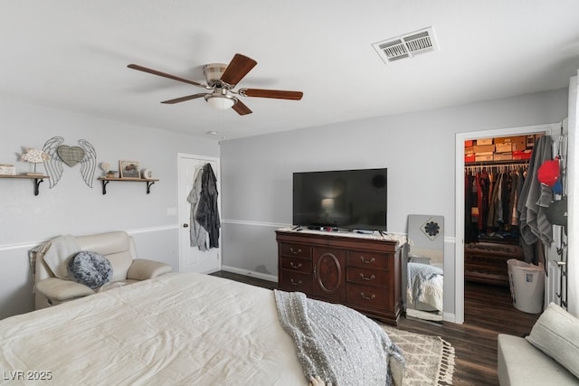 bedroom with ceiling fan, a walk in closet, dark hardwood / wood-style flooring, and a closet