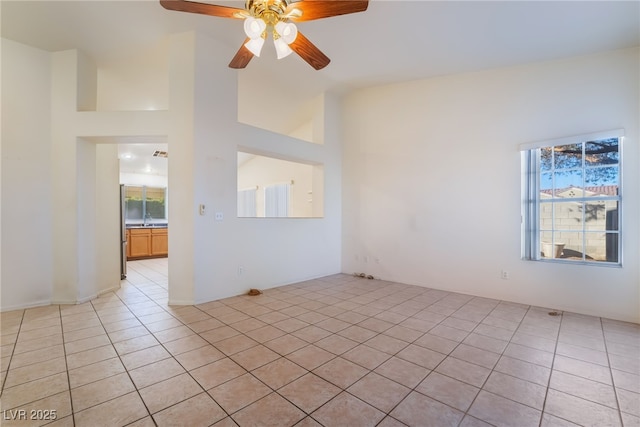 tiled spare room featuring vaulted ceiling, sink, and ceiling fan