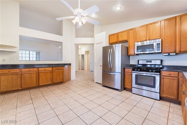 kitchen with ceiling fan, appliances with stainless steel finishes, vaulted ceiling, and light tile patterned floors