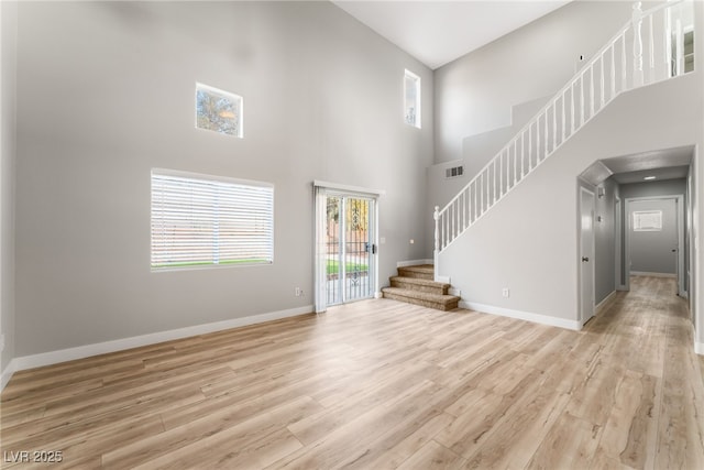 unfurnished living room with a high ceiling and light wood-type flooring