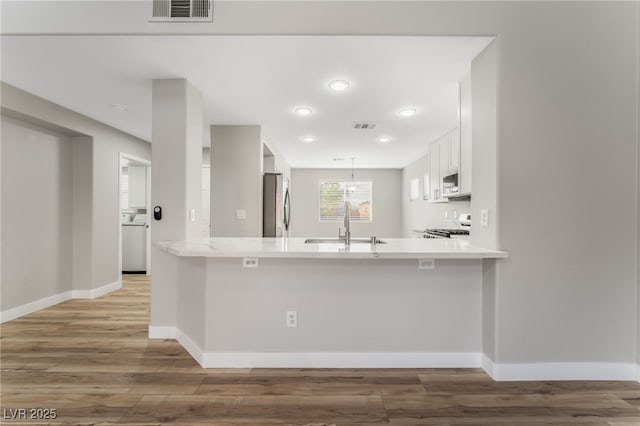 kitchen with sink, stainless steel appliances, kitchen peninsula, and white cabinets