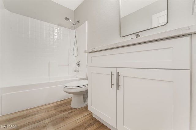 full bathroom with hardwood / wood-style flooring, vanity, shower / bathtub combination, and toilet