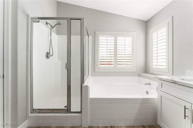 bathroom with independent shower and bath, vaulted ceiling, and vanity