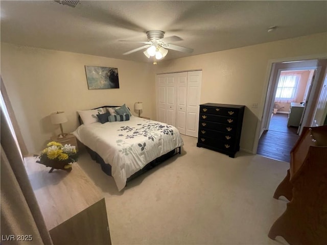 carpeted bedroom with ceiling fan and a closet