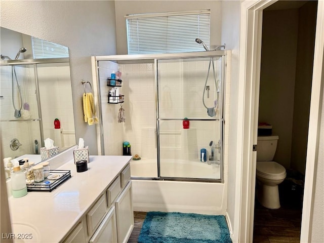 full bathroom with enclosed tub / shower combo, wood-type flooring, vanity, and toilet