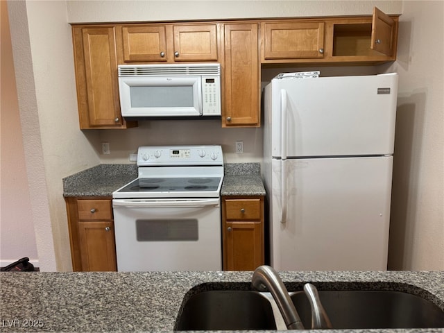 kitchen with white appliances, sink, and dark stone countertops