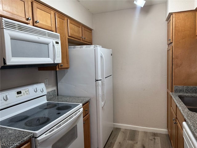 kitchen featuring dark stone countertops, white appliances, and light hardwood / wood-style flooring