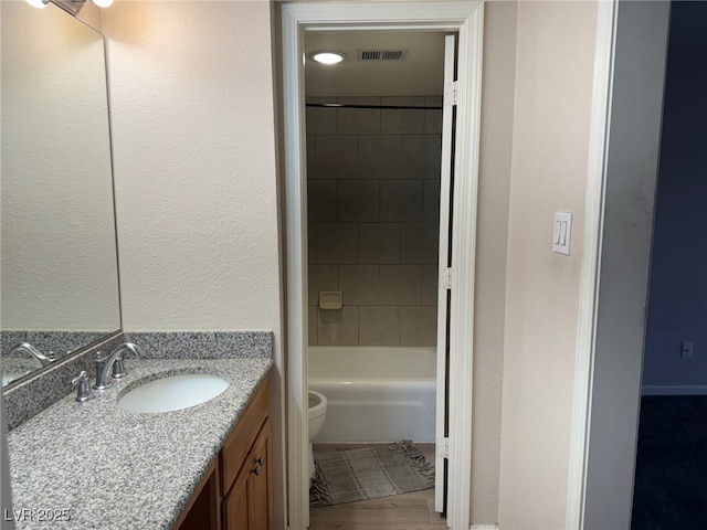 full bathroom featuring vanity, toilet, tiled shower / bath combo, and wood-type flooring