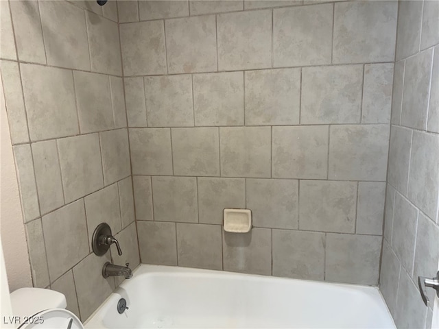 bathroom with tiled shower / bath and toilet