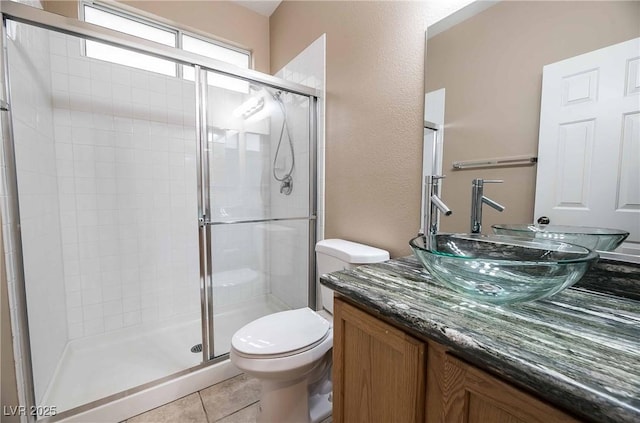 bathroom featuring tile patterned flooring, toilet, vanity, and walk in shower