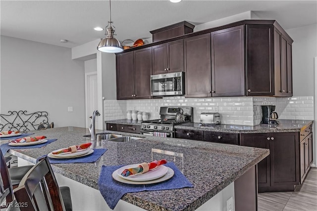 kitchen with sink, backsplash, stainless steel appliances, and hanging light fixtures