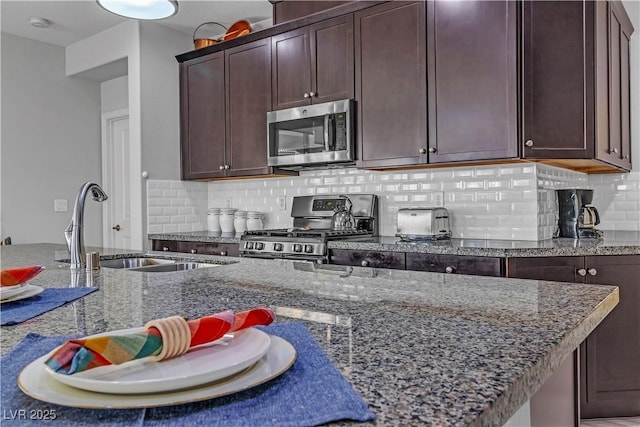 kitchen featuring stone counters, appliances with stainless steel finishes, sink, backsplash, and dark brown cabinetry