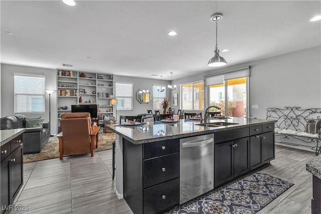 kitchen with pendant lighting, an island with sink, dishwasher, sink, and an inviting chandelier