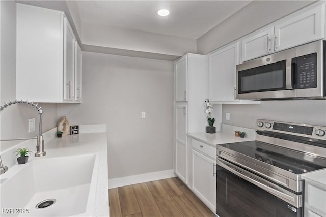 kitchen featuring white cabinetry, appliances with stainless steel finishes, sink, and light wood-type flooring