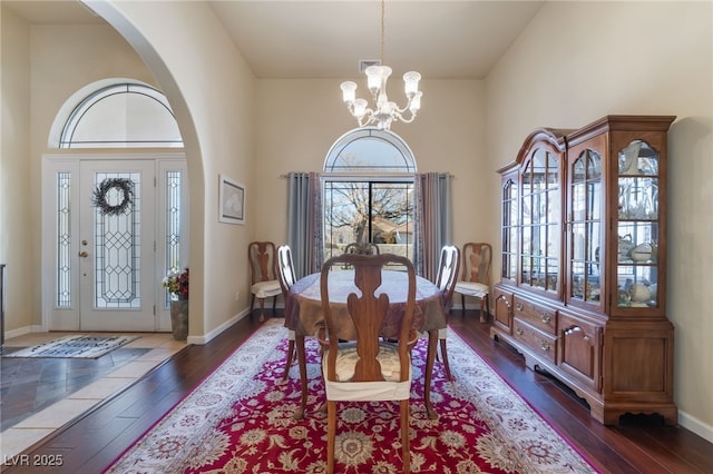 dining area with a towering ceiling, dark hardwood / wood-style flooring, and a chandelier