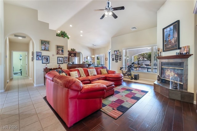 living room featuring a tiled fireplace, high vaulted ceiling, ceiling fan, and light wood-type flooring