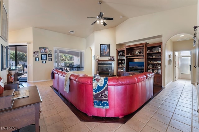 living room featuring lofted ceiling, light tile patterned floors, a tile fireplace, and ceiling fan