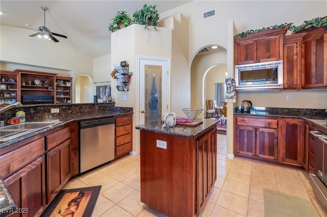 kitchen with light tile patterned flooring, stainless steel appliances, sink, and dark stone counters