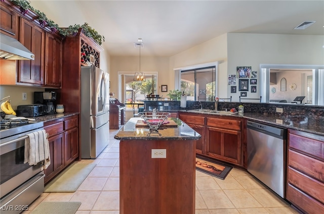 kitchen with sink, decorative light fixtures, light tile patterned floors, appliances with stainless steel finishes, and a kitchen island