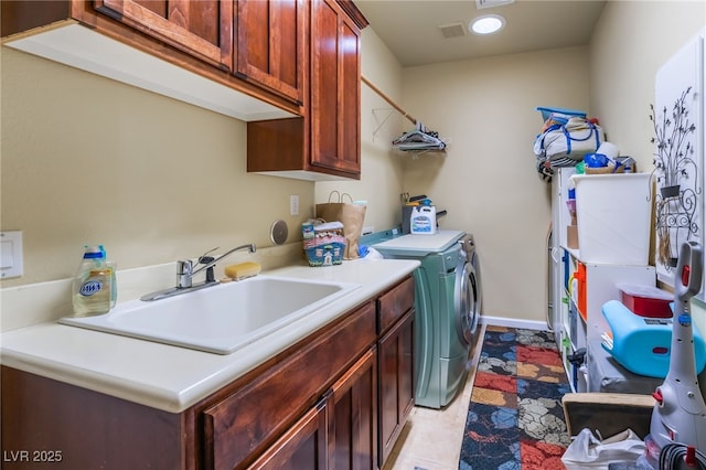 clothes washing area featuring cabinets, sink, and washer and dryer