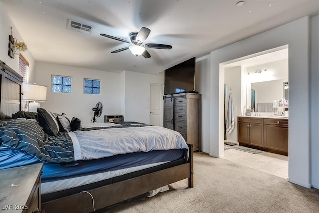 bedroom featuring light carpet, connected bathroom, and ceiling fan