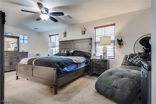 bedroom featuring ceiling fan, light colored carpet, and multiple windows