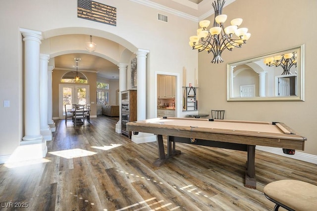 rec room featuring decorative columns, visible vents, arched walkways, wood finished floors, and crown molding