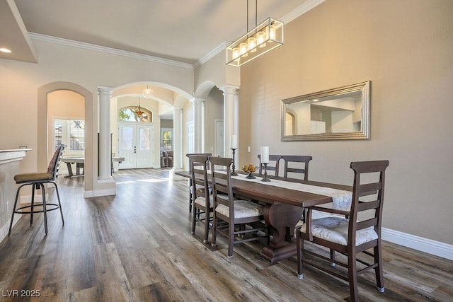 dining space with arched walkways, baseboards, french doors, dark wood finished floors, and ornate columns