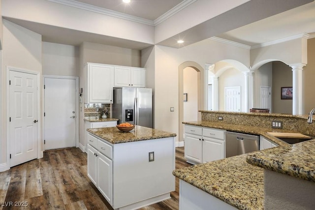 kitchen featuring a center island, appliances with stainless steel finishes, stone countertops, white cabinets, and a sink