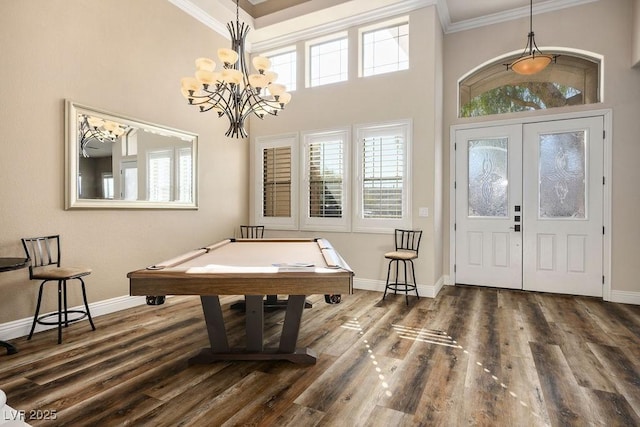 rec room with ornamental molding, dark wood-type flooring, a wealth of natural light, and baseboards