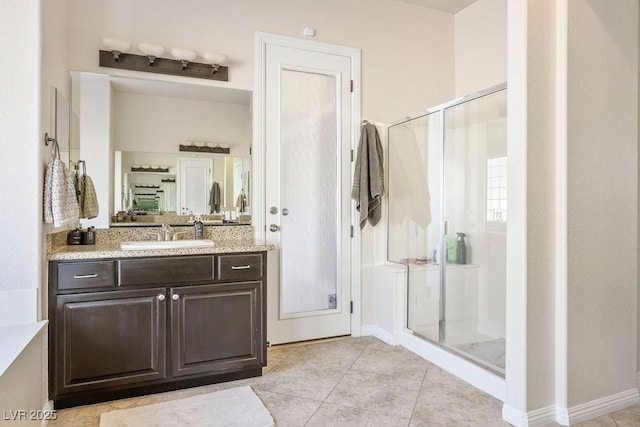 bathroom with tile patterned flooring, a shower stall, vanity, and baseboards